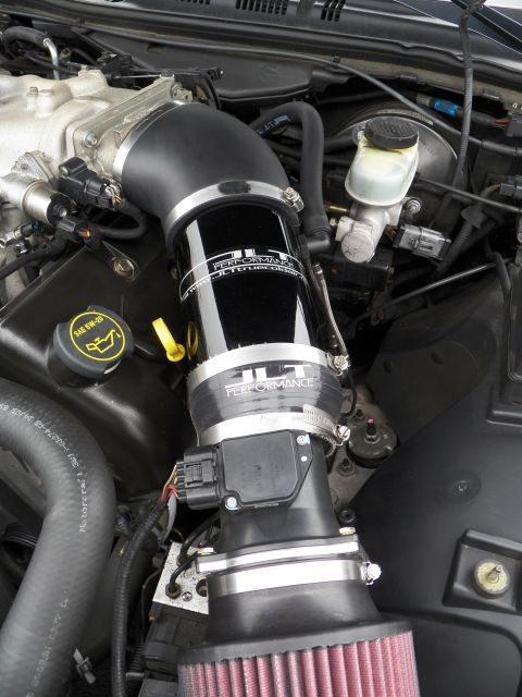 2003 Ford Crown Victoria - Close-up of a black JLT Performance cold air intake tube with brake fluid reservoir nearby in an engine bay