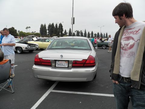 2003 Ford Crown Victoria - man stands behind a silver Mercury Grand Marquis viewing its taillights and trunk at an outdoor show