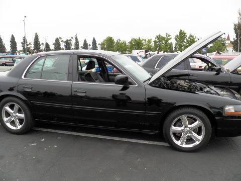 2003 Ford Crown Victoria - Side view of a black Mercury Marauder with hood raised and polished five-spoke wheels in a show lot