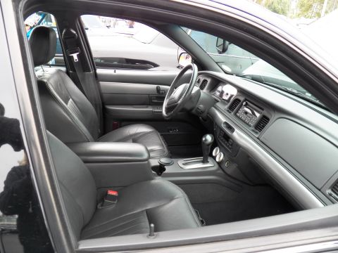 2003 Ford Crown Victoria - Interior shot through open door of a sedan with black leather seats, floor shifter and instrument cluster