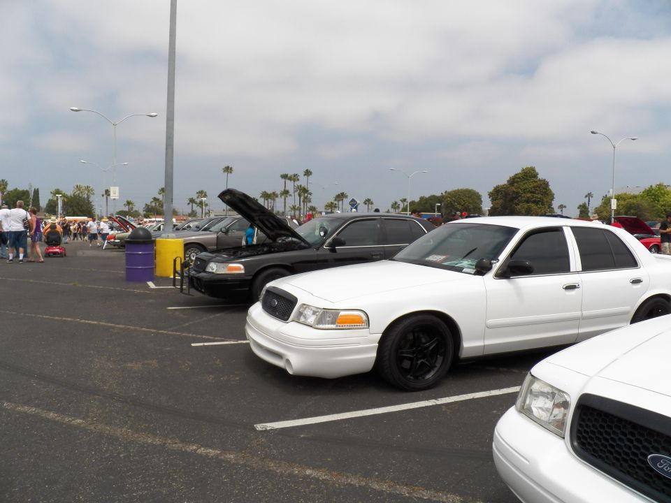 White Ford Crown Victoria sedans with black wheels in car show lot