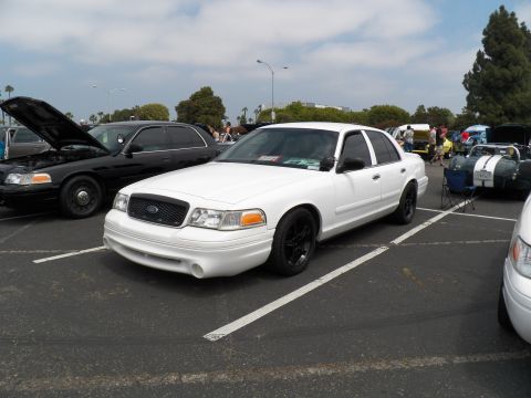 2003 Ford Crown Victoria - Front three-quarter view of a white Ford Crown Victoria on black wheels in a crowded show lot