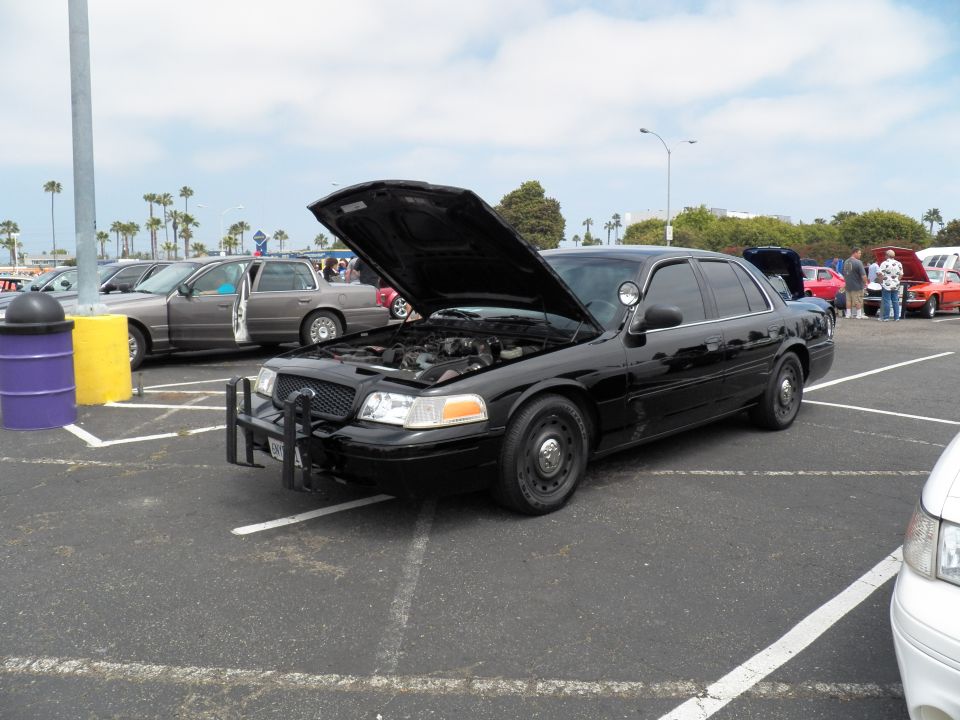 Black Ford Crown Victoria Police Interceptor with hood up and push bar at car show