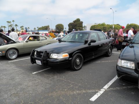 2003 Ford Crown Victoria - Front three-quarter view of black Crown Vic with push bar and California plate among parked show cars