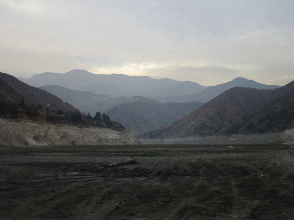 Dry lakebed with mountains under a hazy overcast sky
