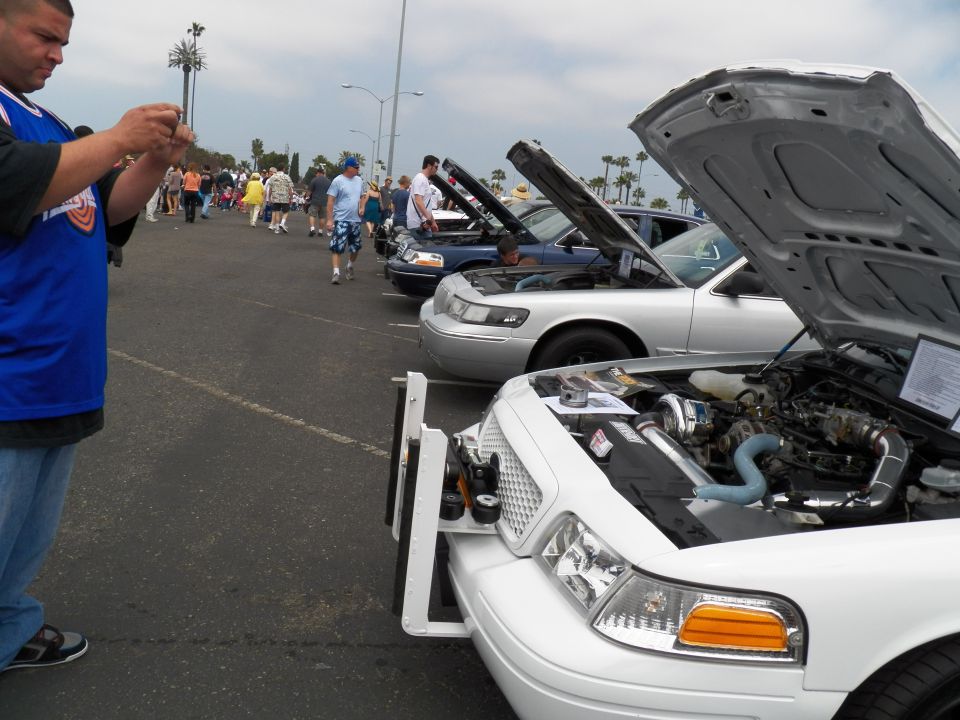 White Ford Crown Victoria with open hood and chrome air intake at car show