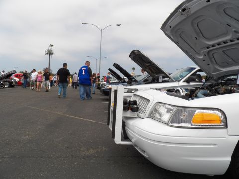 2003 Ford Crown Victoria - Low-angle view of white Crown Vic front corner with open hood, spectators and sedans in background