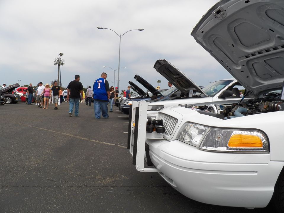 White Ford Crown Victoria headlight and open hood close-up at car show