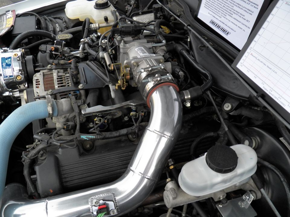 Supercharged V8 engine bay with polished intake piping and Vortech blower