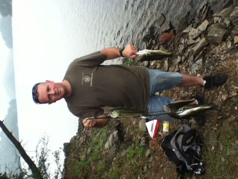 1989 Ford Bronco - A man proudly displays his catch of the day by the water's edge.