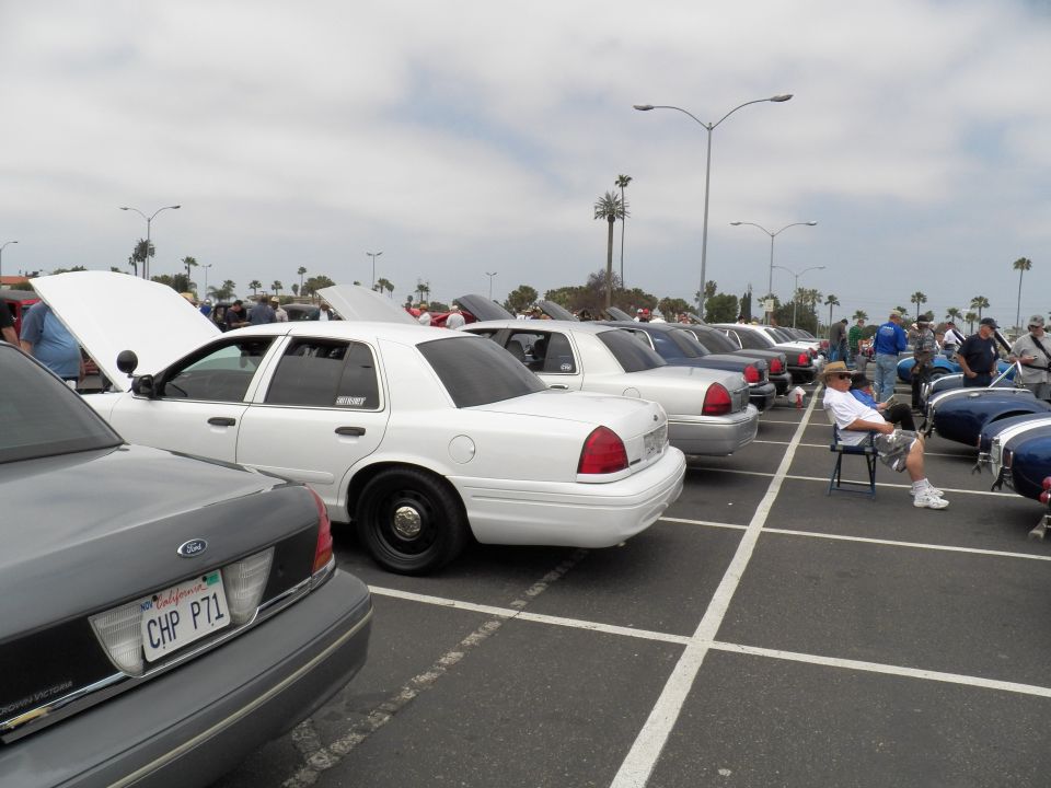White Ford Crown Victoria with CHP P71 plate among parked sedans