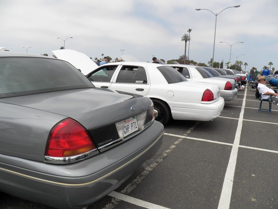 Rear of gray Ford Crown Victoria with CHP P7L plate beside white sedans