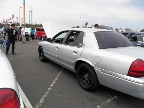 2003 Ford Crown Victoria - Hood-up silver Crown Victoria parked beside other show cars, roller coaster in background