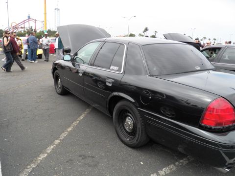 2003 Ford Crown Victoria - Black Crown Victoria parked hood-up; crowd and roller coaster visible behind the lot