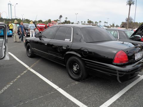 2003 Ford Crown Victoria - Black Crown Victoria in parking lot with hot rods and spectators in straw hats behind