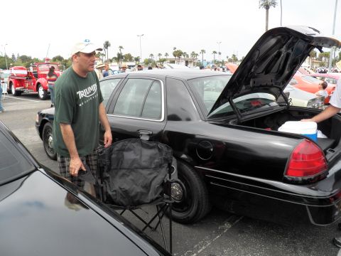 2003 Ford Crown Victoria - Spectator in cap stands by black Crown Victoria with trunk open and cooler inside