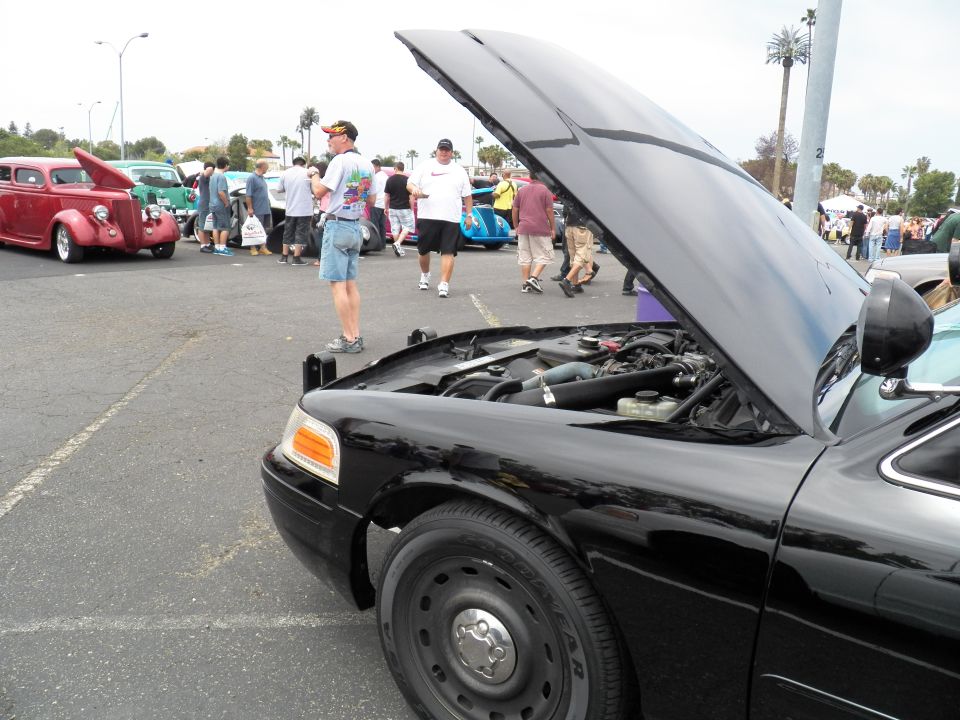 Black Ford Crown Victoria front three-quarter with hood up and engine visible at car show