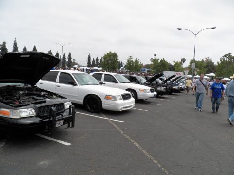 2003 Ford Crown Victoria - Crown Victoria show row under gray sky with spectators walking along the pavement
