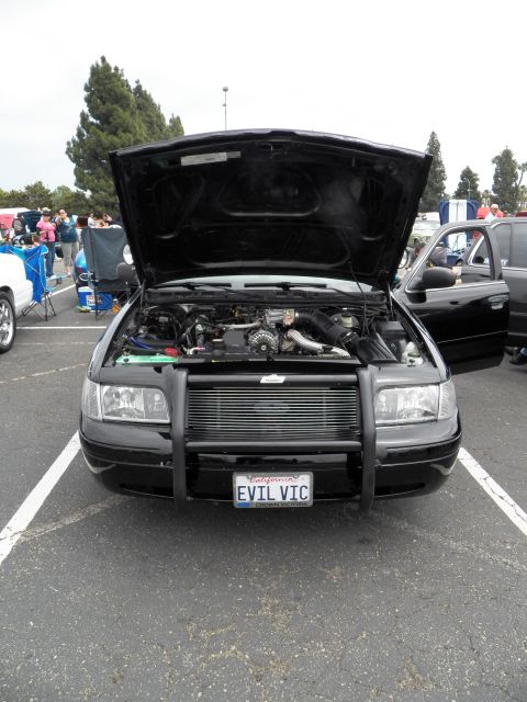 2003 Ford Crown Victoria - Police-style sedan with grille guard and vanity plate parked at a car meet