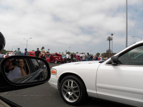 2003 Ford Crown Victoria - View past a side mirror toward white sedans and spectators at an outdoor event