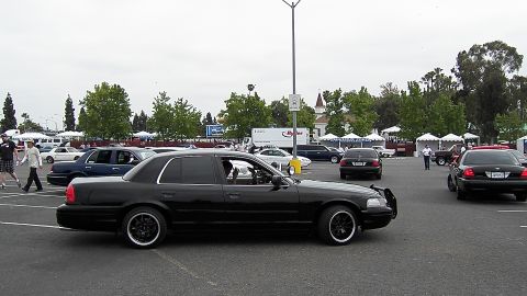 2003 Ford Crown Victoria - Side profile of a lowered black Crown Victoria with blacked-out wheels in a busy parking lot