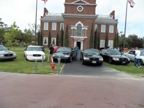 2003 Ford Crown Victoria - Black and white Crown Victoria sedans face a brick building with bunting, a fire hydrant nearby