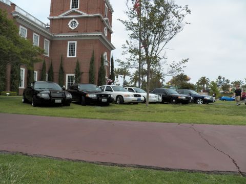 2003 Ford Crown Victoria - Crown Victoria Police Interceptors lined on a lawn beside a brick building with a cracked walkway
