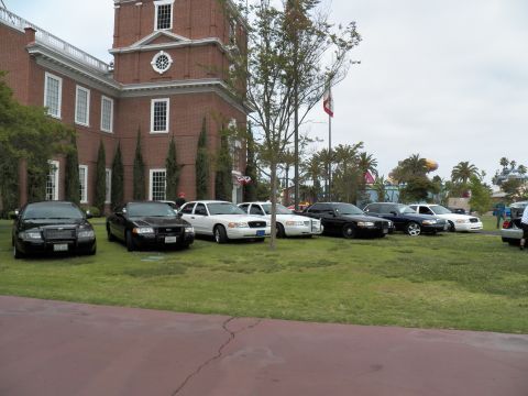 2003 Ford Crown Victoria - Black, white and silver Crown Victoria sedans parked across a lawn near a brick building