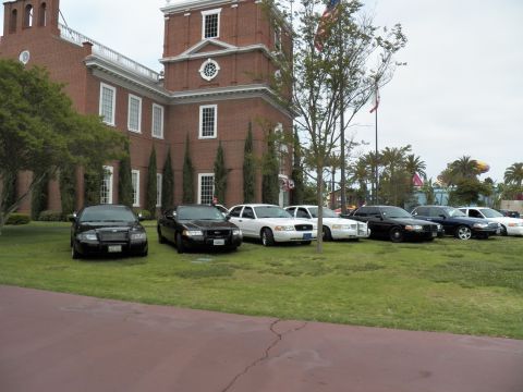 2003 Ford Crown Victoria - Black and white Crown Victoria sedans on a lawn under a sapling beside a brick building