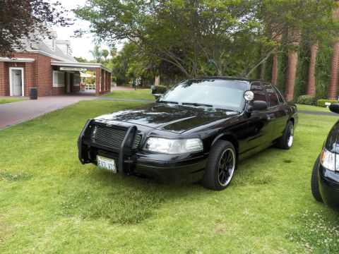2003 Ford Crown Victoria - Glossy black Crown Victoria with grille guard and pillar spotlight parked on grass, EVIL VTC plate