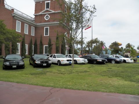 2003 Ford Crown Victoria - Lineup of black and white Crown Victoria sedans on grass in front of a brick Independence Hall replica.
