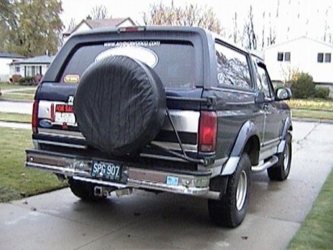 1995 Ford Bronco - This Ford Bronco is parked on a wet driveway with houses in the background.