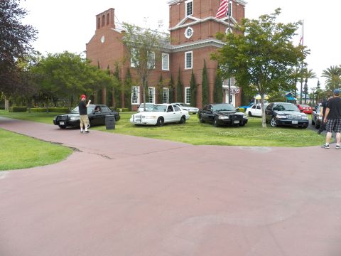 2003 Ford Crown Victoria - People stand among Crown Victoria sedans on grass in front of a brick Independence Hall replica.