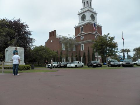 2003 Ford Crown Victoria - Person looks at a pedestal statue as sedans sit parked on the lawn beside a brick hall.