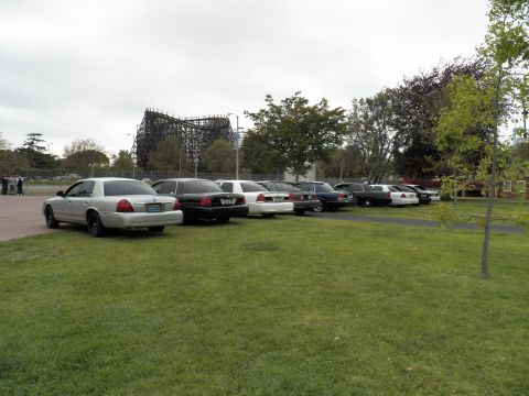 2003 Ford Crown Victoria - Lead white sedan with a wooden roller coaster behind a lineup of Ford and Mercury cars
