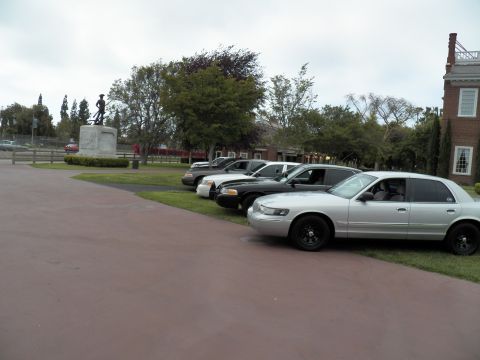 2003 Ford Crown Victoria - Silver full-size sedan with black wheels at front of a row by a soldier statue and brick hall