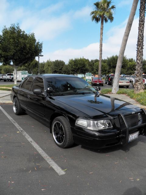 2003 Ford Crown Victoria - Black full-size sedan with tinted windows, black wheels and front push bar in a parking lot