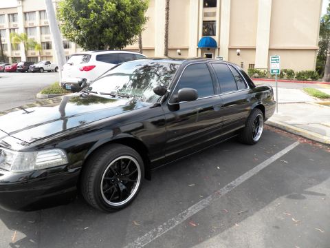 2003 Ford Crown Victoria - Lowered black Crown Victoria on black wheels, tinted windows, building behind.