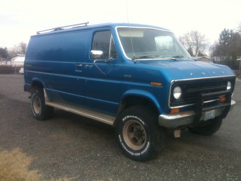 1977 Ford E350 - This blue Ford van is equipped with off-road tires and a roof rack, suggesting it's built for utility or adventure.