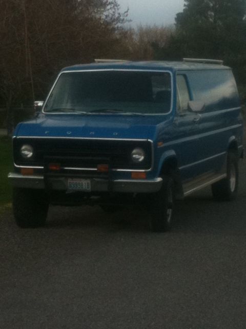 1977 Ford E350 - This blue panel van has a custom front bumper with auxiliary lights and a visible license plate.