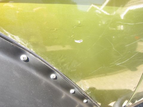 1974 Ford Bronco - Close-up of a green fender flare, showing signs of wear and tear with visible screws.