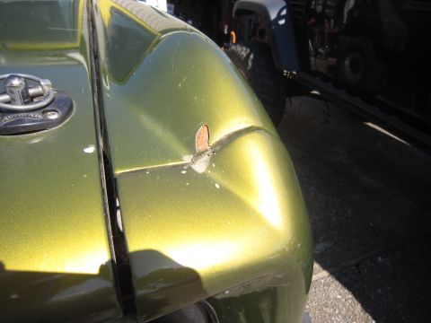 1974 Ford Bronco - Close-up of a green vehicle's fender and gas cap, with another vehicle in the background.