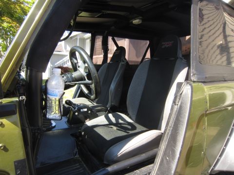 1974 Ford Bronco - The interior of a modified off-road vehicle features aftermarket seats and a roll cage, with a water bottle in the center console.