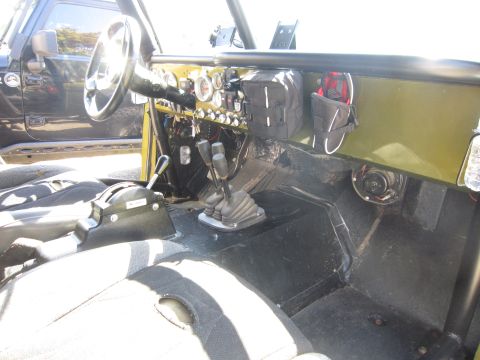 1974 Ford Bronco - Custom interior features multiple shifters and a dashboard filled with gauges, suggesting off-road modifications.