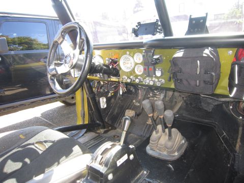 1974 Ford Bronco - Custom interior of an off-road vehicle, aftermarket gauges and controls. Another vehicle is partially visible.