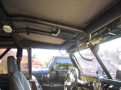 1974 Ford Bronco - The interior of a Jeep shows a CB radio and roll cage, with another Jeep parked outside.
