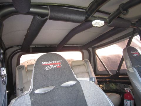 1974 Ford Bronco - The interior of a vehicle shows a roll cage and racing seats, with a fire extinguisher visible.