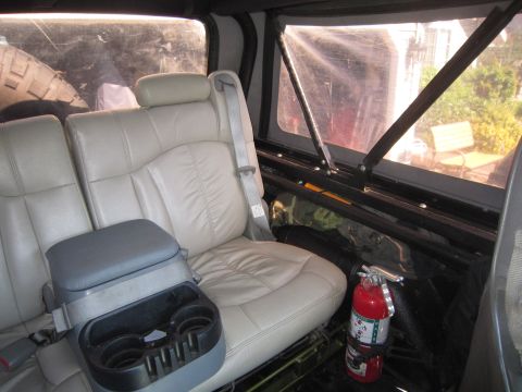 1974 Ford Bronco - The interior features leather seats, a center console with cup holders, and a mounted fire extinguisher.