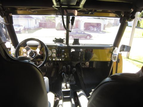 1974 Ford Bronco - The interior of a modified vehicle shows a custom steering wheel and dashboard with multiple gauges.