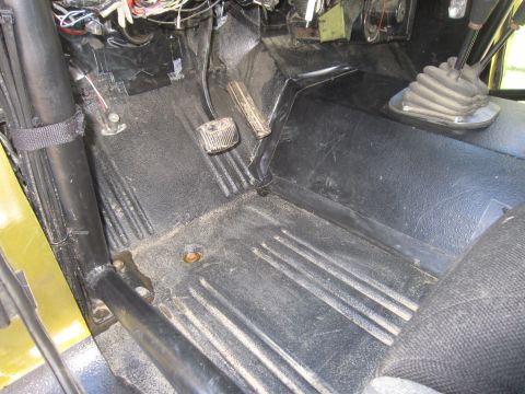 1974 Ford Bronco - The interior floor of a 1974 Ford Bronco shows the pedals, shifter boot, and wiring.